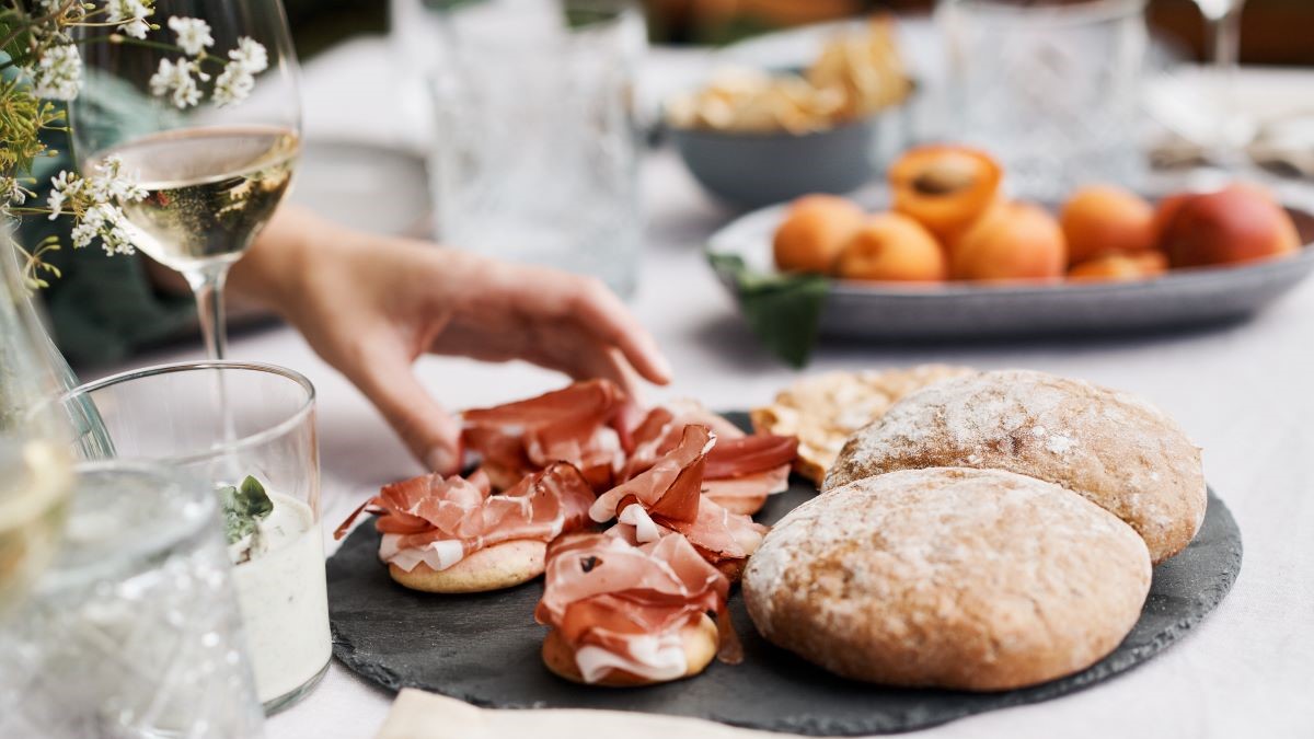 Festlich gedeckter Tisch mit verschiedenen lokalen Produkten, darunter Südtiroler Speck.