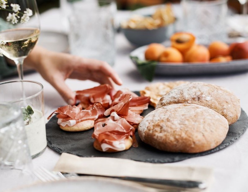 Festlich gedeckter Tisch mit verschiedenen lokalen Produkten, darunter Südtiroler Speck.