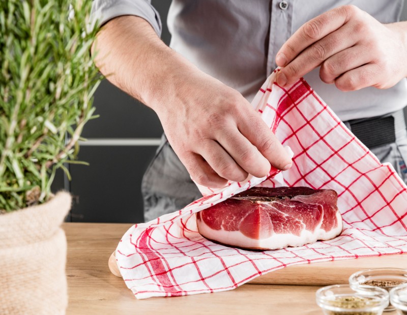 Ein Stück Südtiroler Speck g.g.A. wird in ein feuchtes Stofftuch gewickelt zur Aufbewahrung.