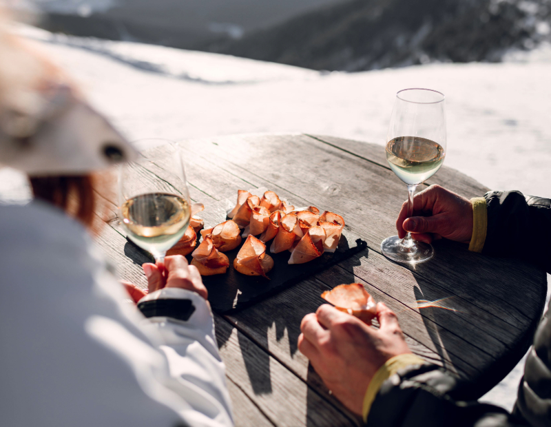 Aperitif mit 2 Gläsern Weißwein und Häppchen mit Speck