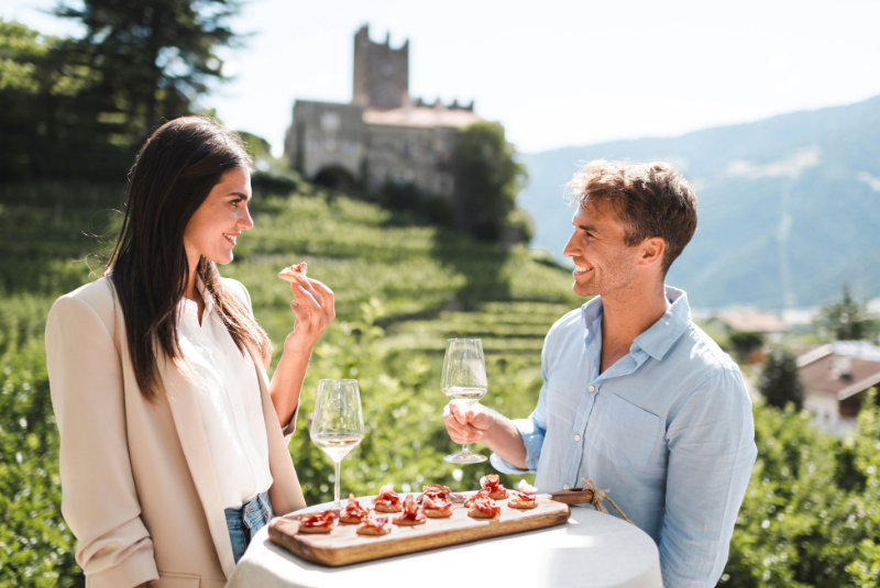 Ein junger Mann und eine junge Frau genießen einen Aperitif mit Blick auf das Schloss