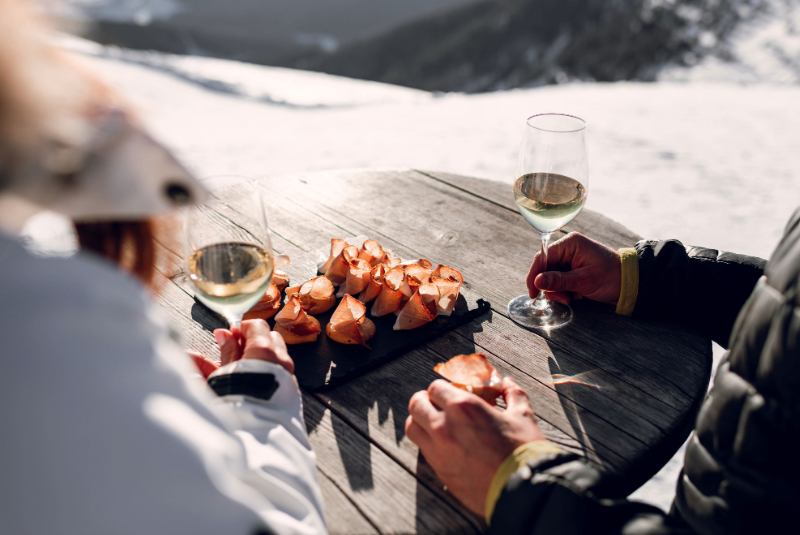 Aperitif mit 2 Gläsern Weißwein und Häppchen mit Speck