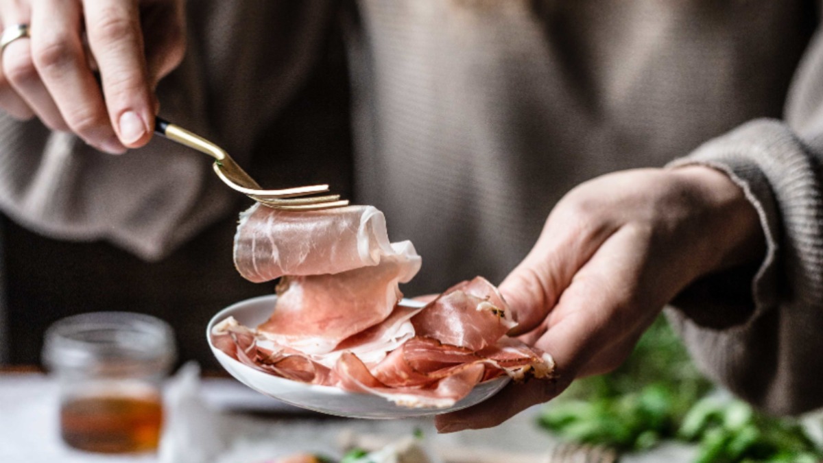Dünne Scheiben Speck auf einem weißen Teller.