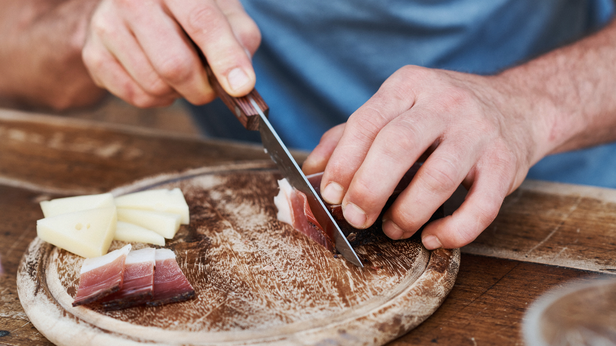Uomo taglia dello speck sul tagliere