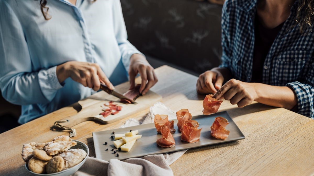 Zwei Mädchen bereiten Häppchen mit Speck zu.