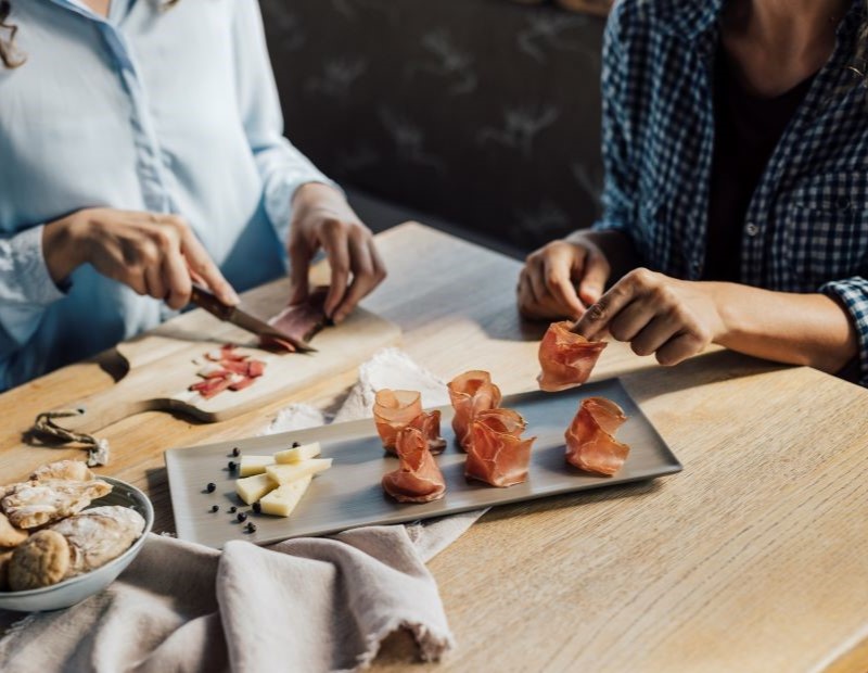 Zwei Mädchen bereiten Häppchen mit Speck zu.