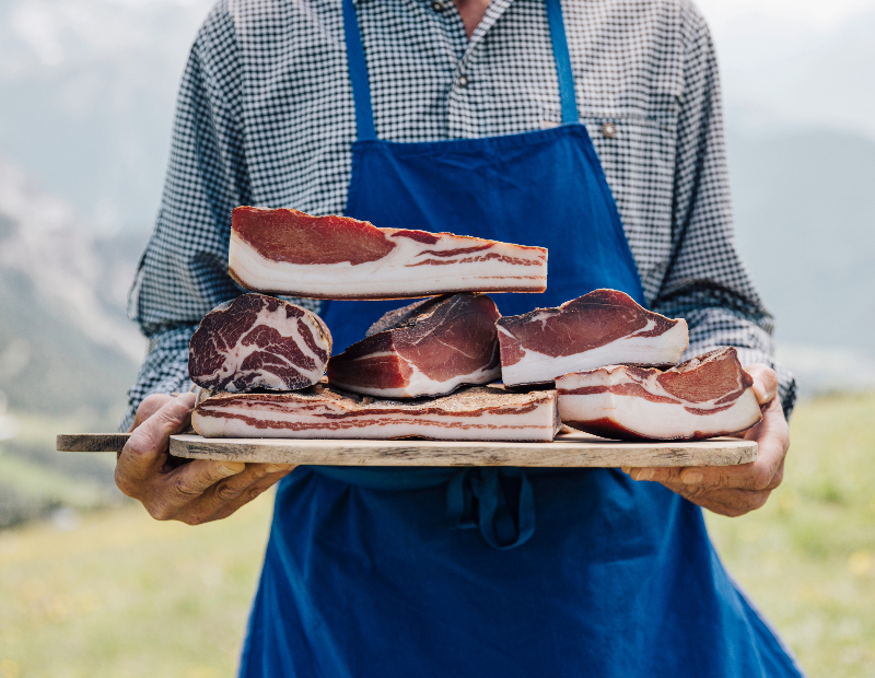 Ein Mann bringt Speck auf das Schneidebrett.